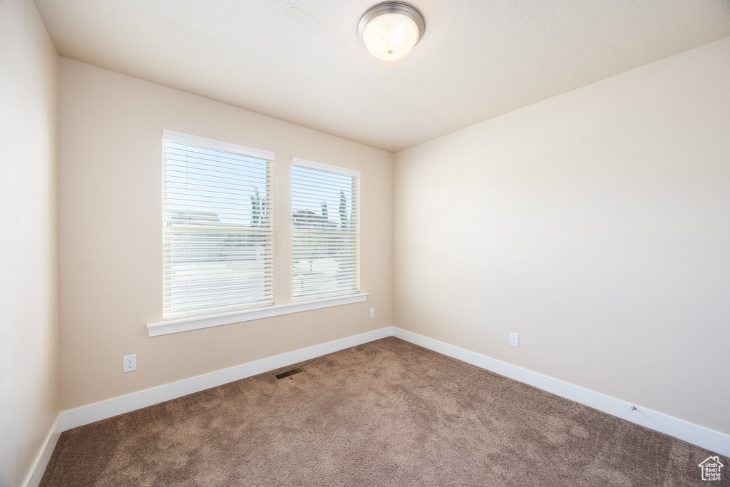 Carpeted spare room featuring baseboards