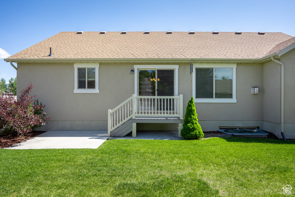Back of property with a patio, stucco siding, a lawn, and roof with shingles
