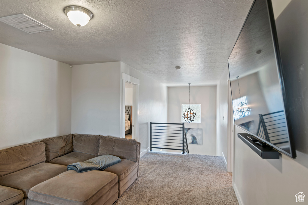 Living area with carpet floors, a chandelier, and a textured ceiling