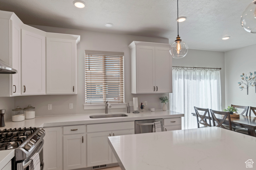 Kitchen with a sink, light countertops, white cabinetry, and recessed lighting