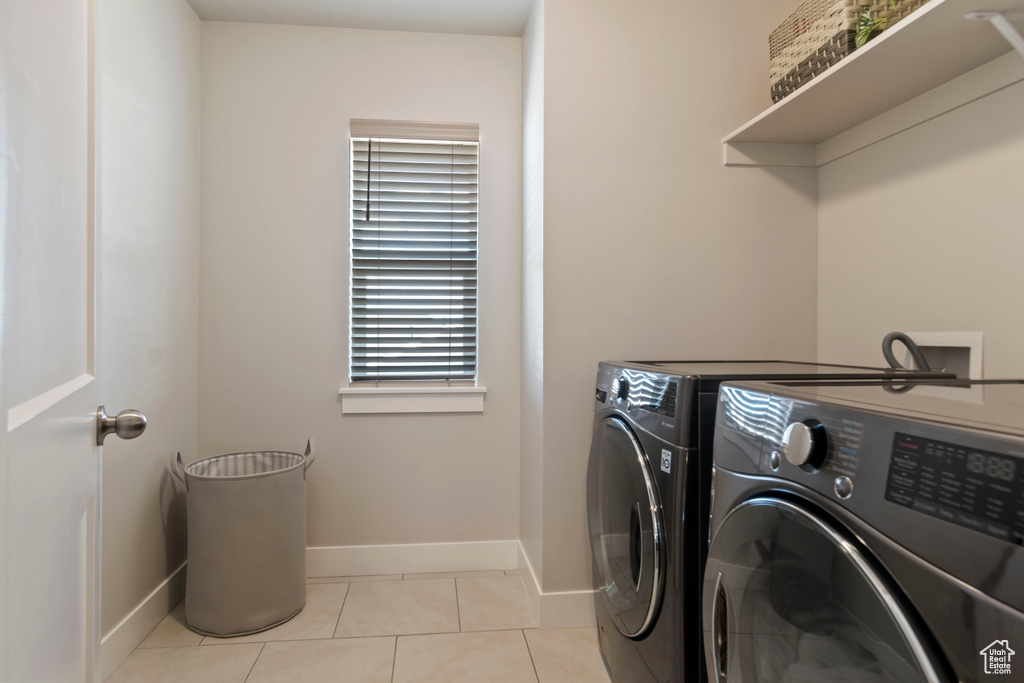 Laundry room with washer and clothes dryer, baseboards, and light tile patterned flooring