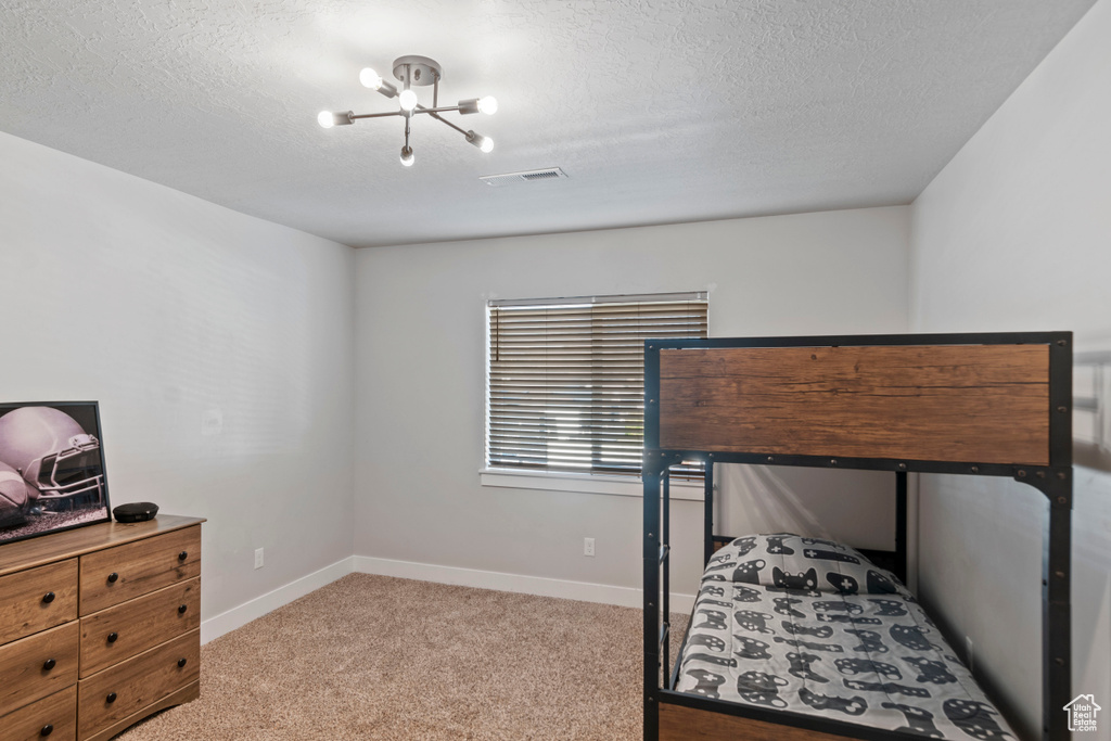 Bedroom with light carpet, baseboards, a chandelier, and a textured ceiling
