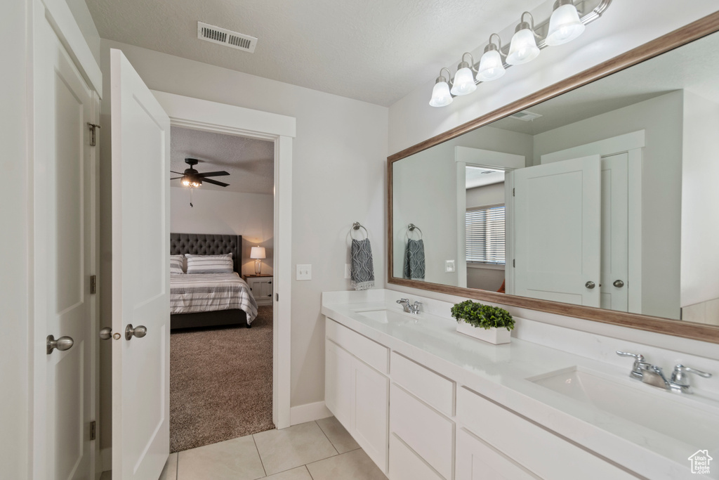 Full bath featuring double vanity, connected bathroom, tile patterned floors, ceiling fan, and baseboards