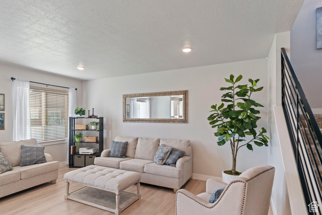 Living area featuring wood finished floors, a textured ceiling, baseboards, and recessed lighting