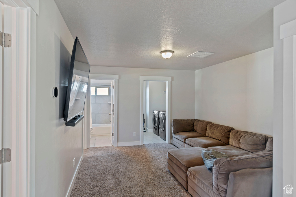 Carpeted living area featuring separate washer and dryer, a textured ceiling, and baseboards