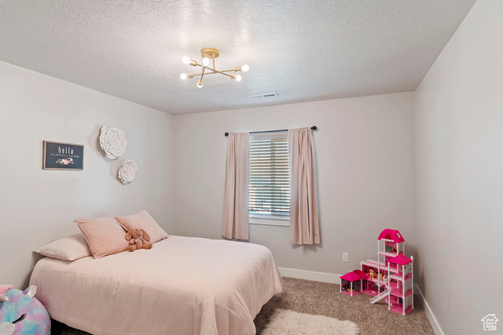 Bedroom with carpet, a chandelier, baseboards, and a textured ceiling