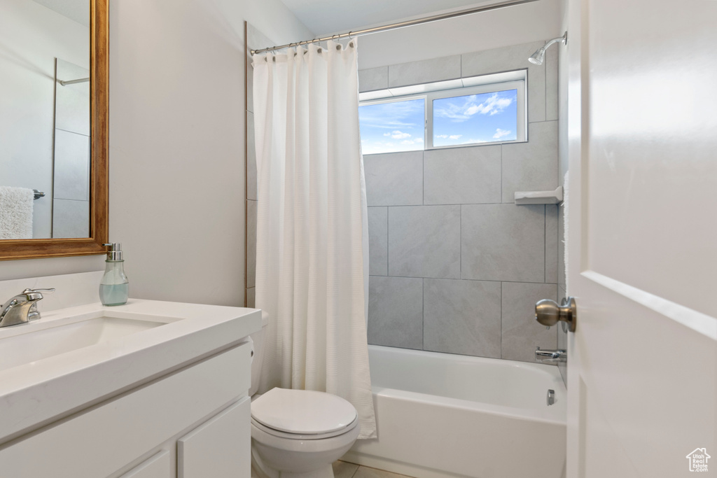 Bathroom with vanity, shower / bathtub combination with curtain, and toilet