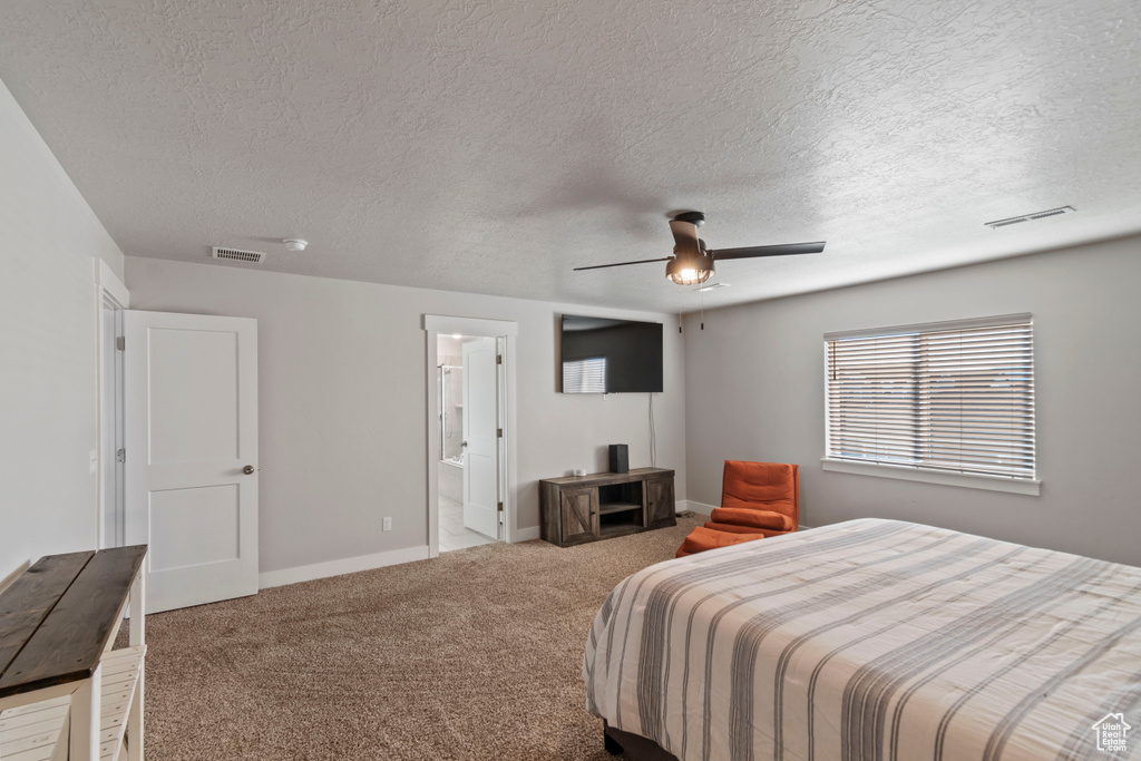 Carpeted bedroom with a textured ceiling, baseboards, and ceiling fan