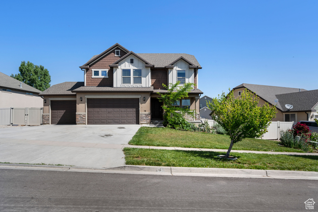 Craftsman-style house with a gate, concrete driveway, stone siding, an attached garage, and stucco siding