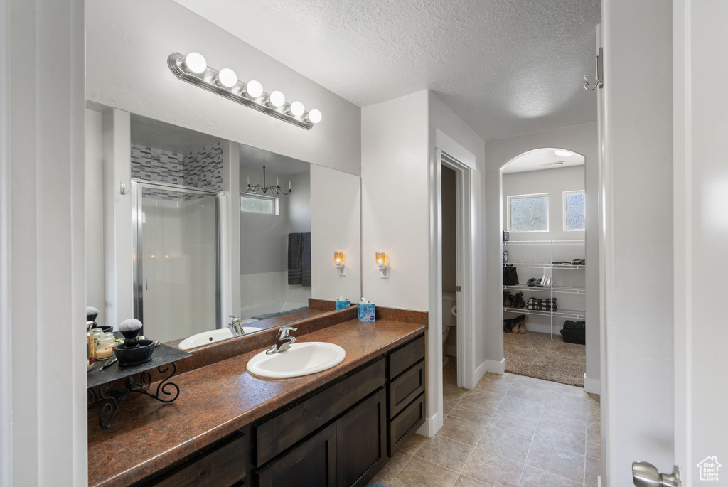 Full bath with a stall shower, vanity, a textured ceiling, toilet, and tile patterned floors