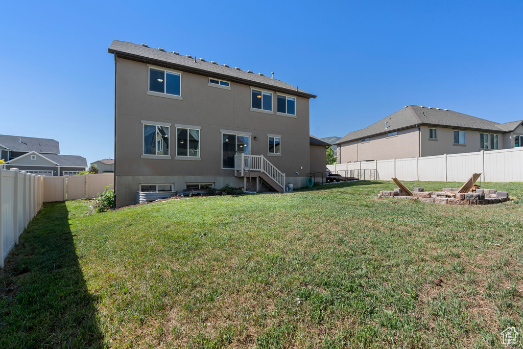 Rear view of property featuring an outdoor fire pit and stucco siding