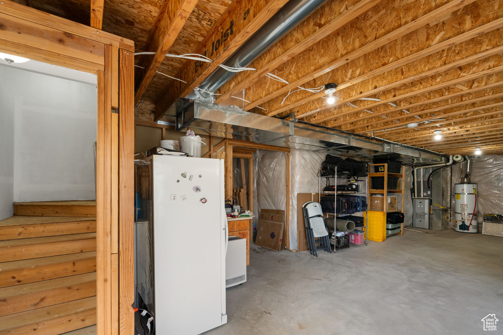 Unfinished below grade area featuring freestanding refrigerator and secured water heater