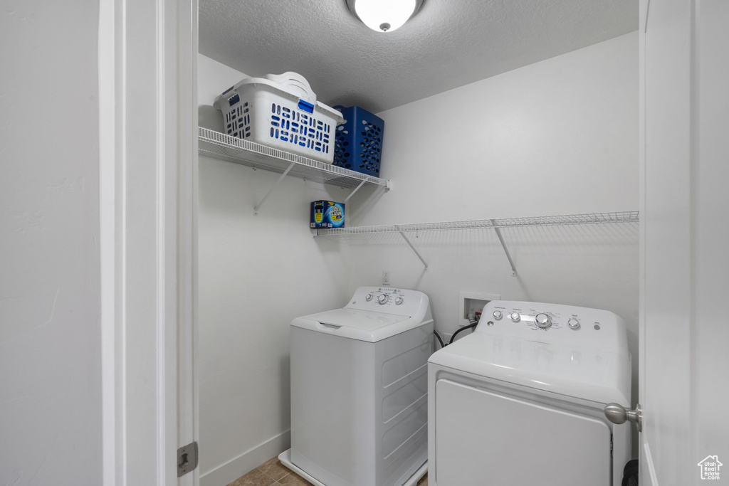 Washroom featuring washing machine and dryer, baseboards, and a textured ceiling