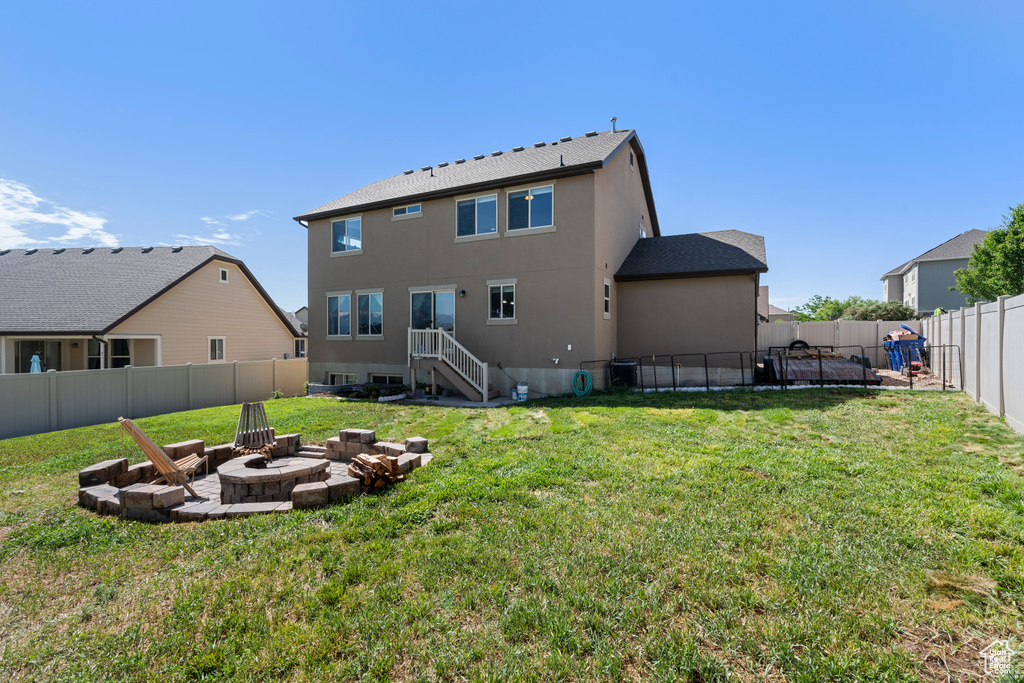 Back of property with an outdoor fire pit and stucco siding