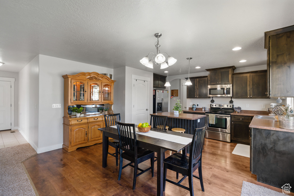 Dining room with a chandelier, recessed lighting, baseboards, and wood finished floors