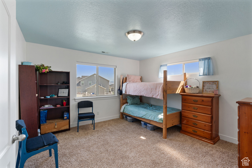 Carpeted bedroom featuring a textured ceiling and baseboards