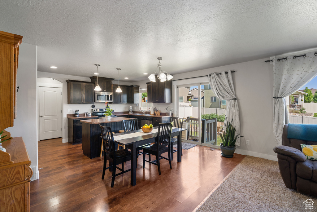 Dining space featuring dark wood finished floors, a textured ceiling, arched walkways, baseboards, and recessed lighting