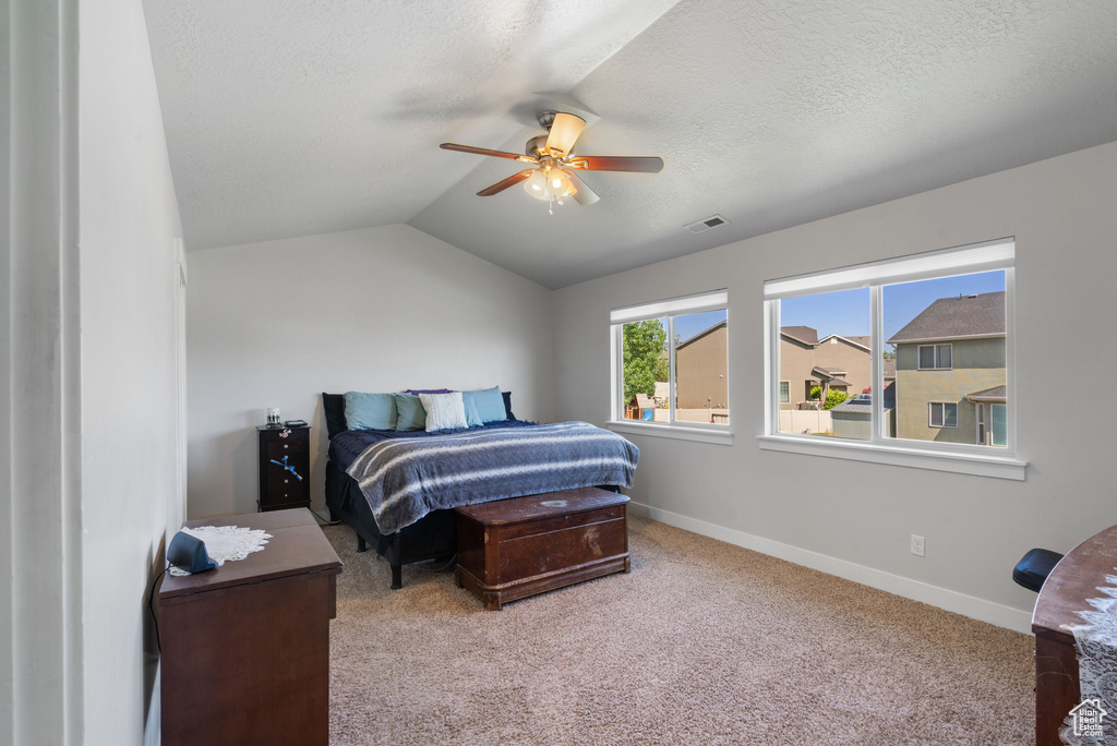 Carpeted bedroom with baseboards, a textured ceiling, lofted ceiling, and a ceiling fan