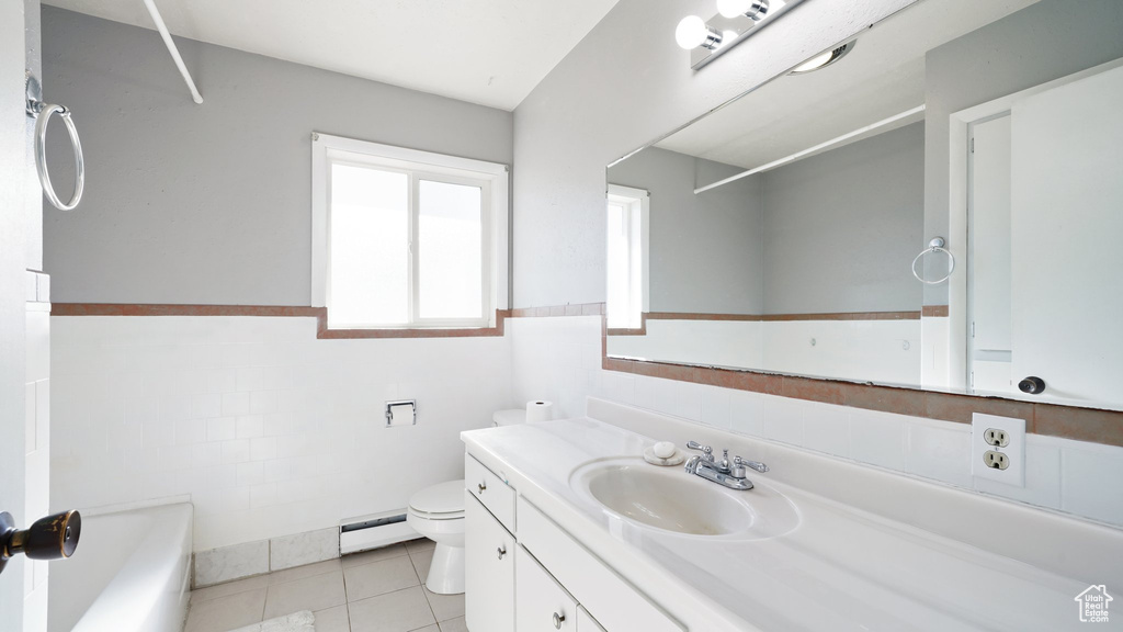 Bathroom with toilet, a bathtub, vanity, a baseboard radiator, and a wainscoted wall