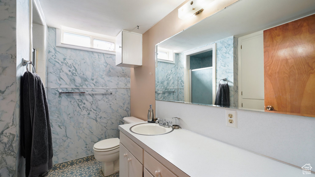 Bathroom featuring vanity, toilet, and a shower with shower door