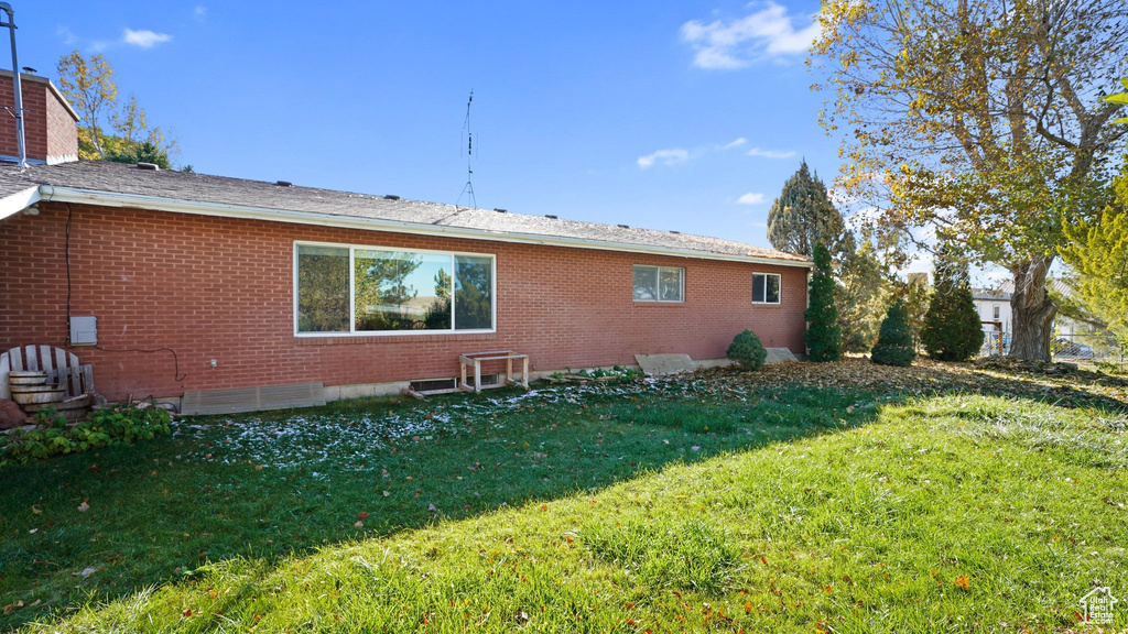 Back of house with brick siding and a lawn
