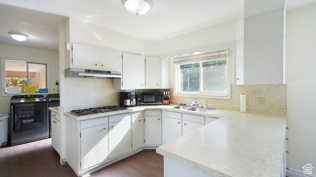 Kitchen featuring washer / clothes dryer, under cabinet range hood, a sink, stainless steel gas stovetop, and black microwave