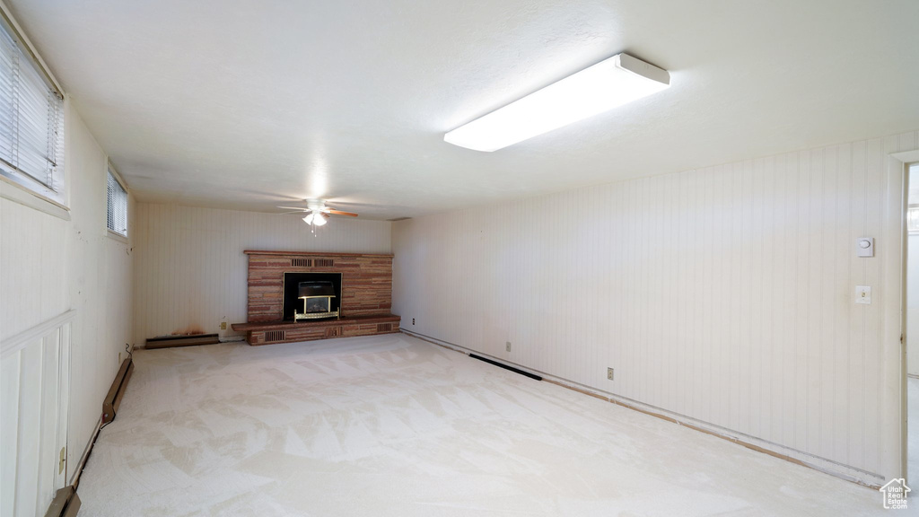 Unfurnished living room with ceiling fan, a glass covered fireplace, and light carpet
