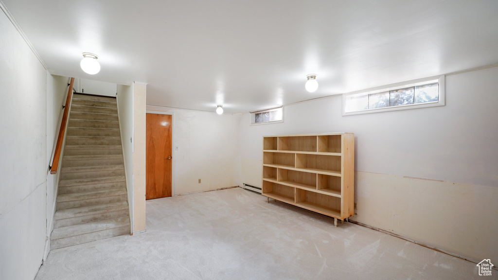 Basement featuring a baseboard heating unit, stairs, and carpet