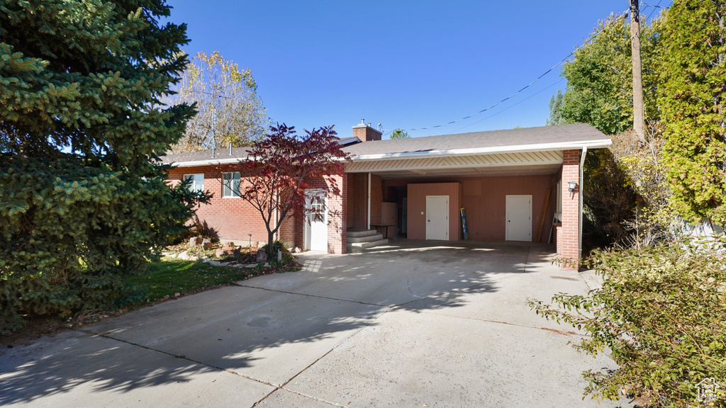Ranch-style home featuring brick siding, driveway, a chimney, and a carport