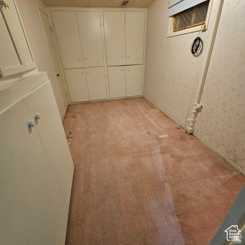 Below grade area with wallpapered walls and light colored carpet