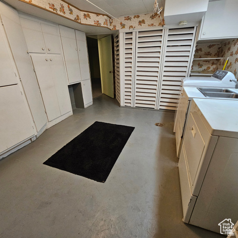 Kitchen with independent washer and dryer, white cabinets, concrete floors, and light countertops