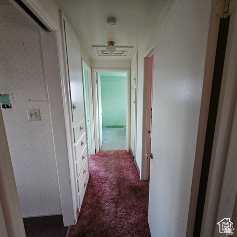 Hallway featuring dark colored carpet