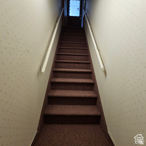 Stairway featuring wallpapered walls