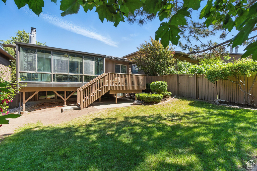 Rear view of house with a sunroom, a deck, and stairs