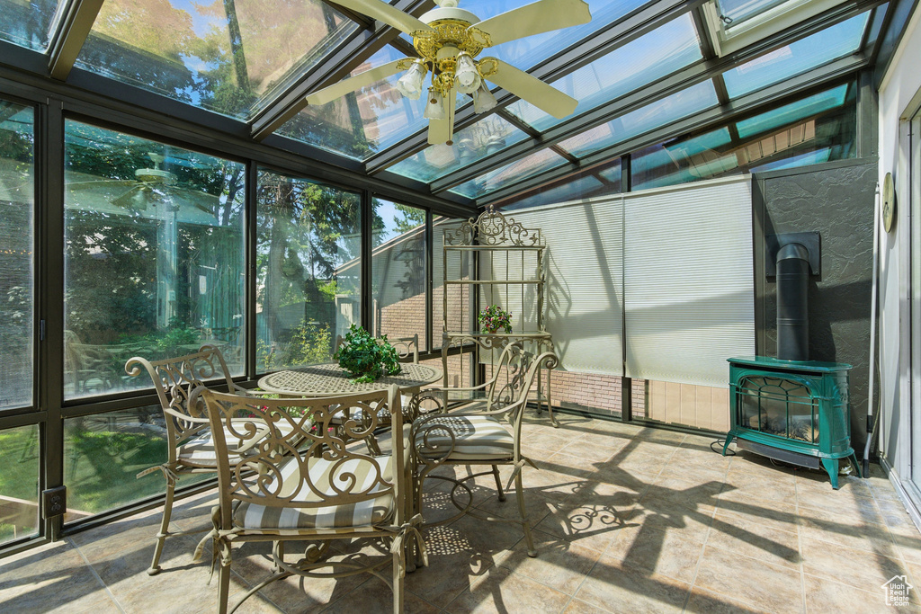 Sunroom / solarium featuring a ceiling fan and a wood stove