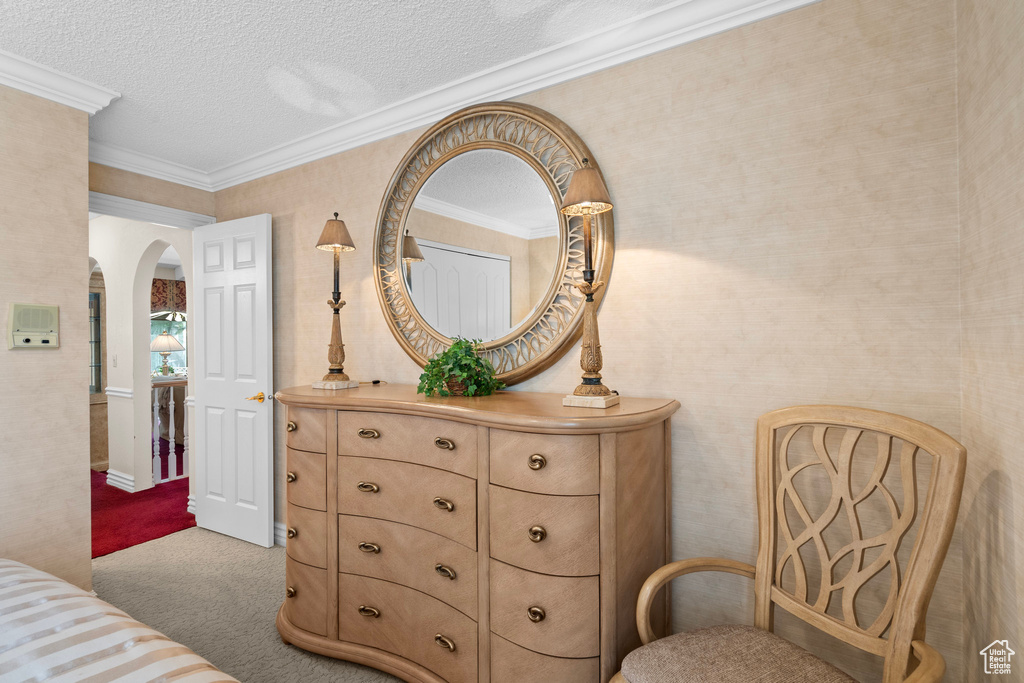 Bedroom featuring arched walkways, carpet flooring, a textured ceiling, and crown molding