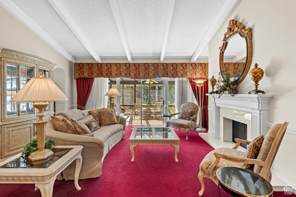 Carpeted living area with a textured ceiling, beamed ceiling, a premium fireplace, and plenty of natural light
