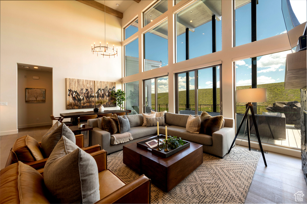 Living room with a high ceiling, a chandelier, baseboards, and wood finished floors