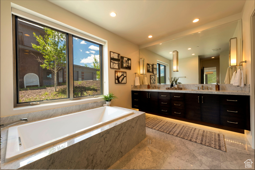 Bathroom with double vanity, a bath, and recessed lighting