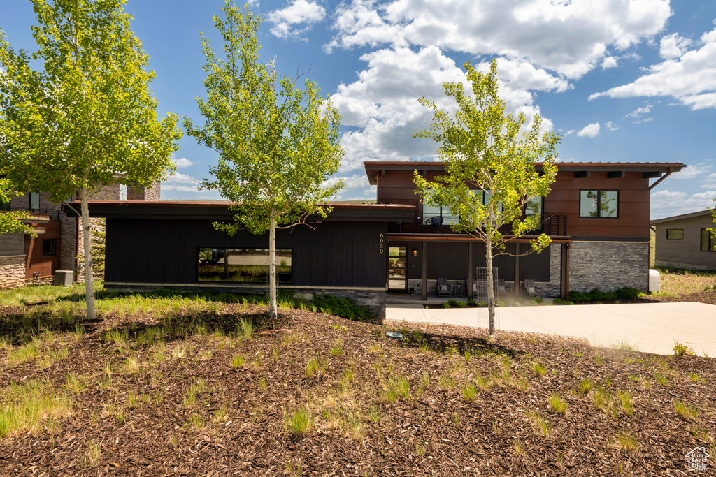View of front of property with a patio area and stone siding