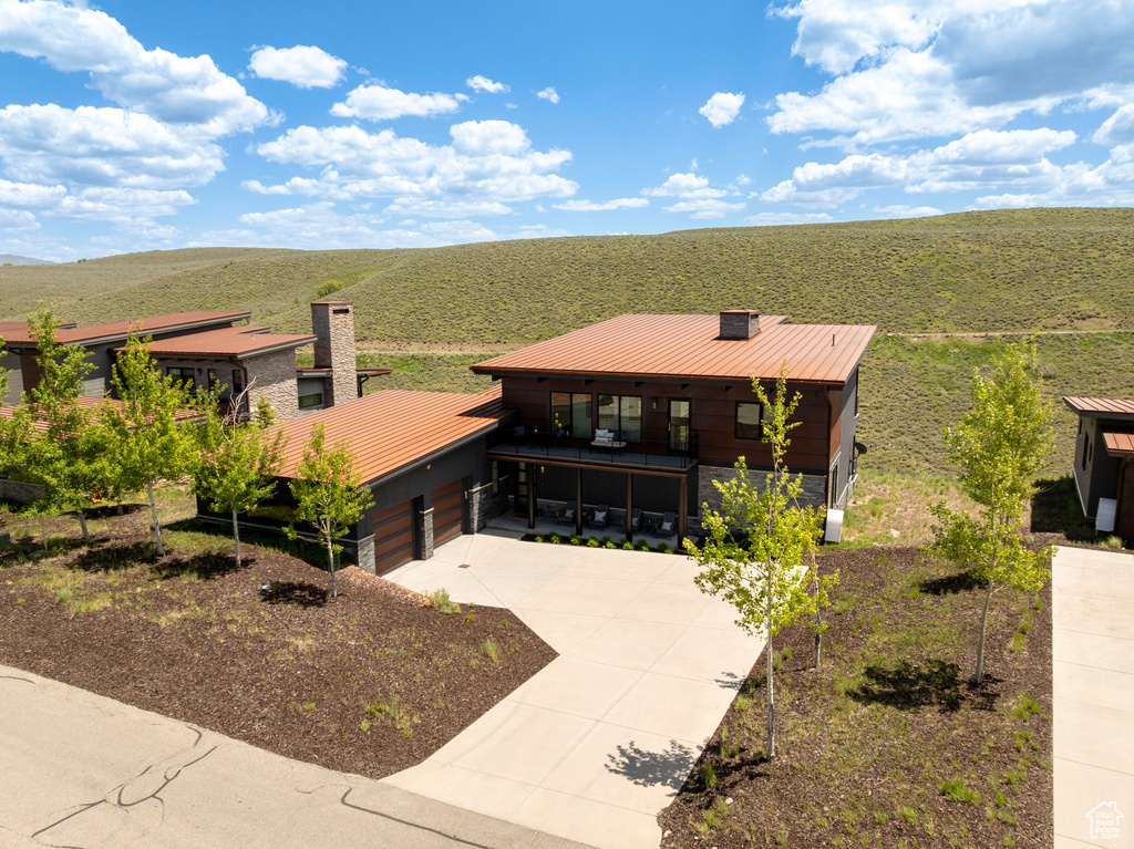 View of front facade featuring a chimney, concrete driveway, metal roof, and a standing seam roof