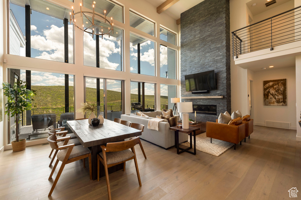Dining space with a towering ceiling, hardwood / wood-style flooring, a fireplace, a chandelier, and baseboards