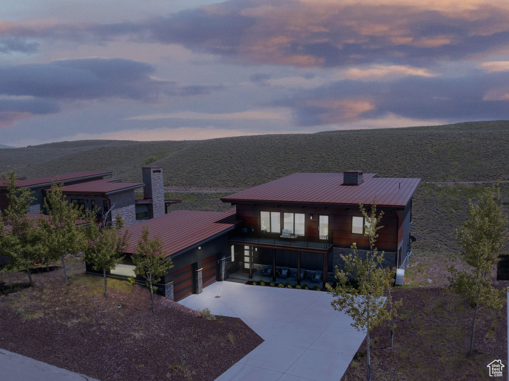 View of front of property featuring a standing seam roof, concrete driveway, a chimney, and a metal roof