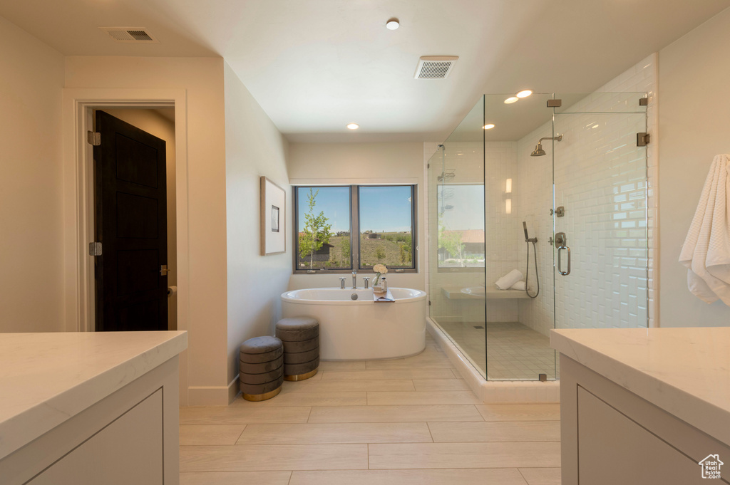 Bathroom featuring a stall shower, a freestanding bath, vanity, wood finish floors, and recessed lighting