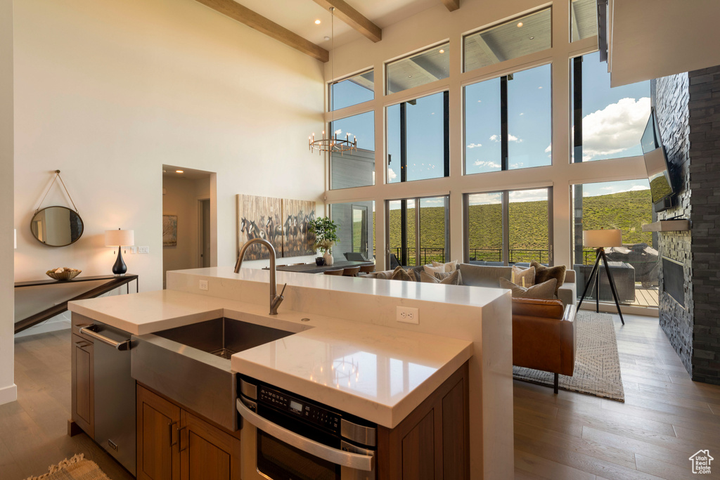 Kitchen featuring open floor plan, a high ceiling, stainless steel appliances, light countertops, and wood finished floors