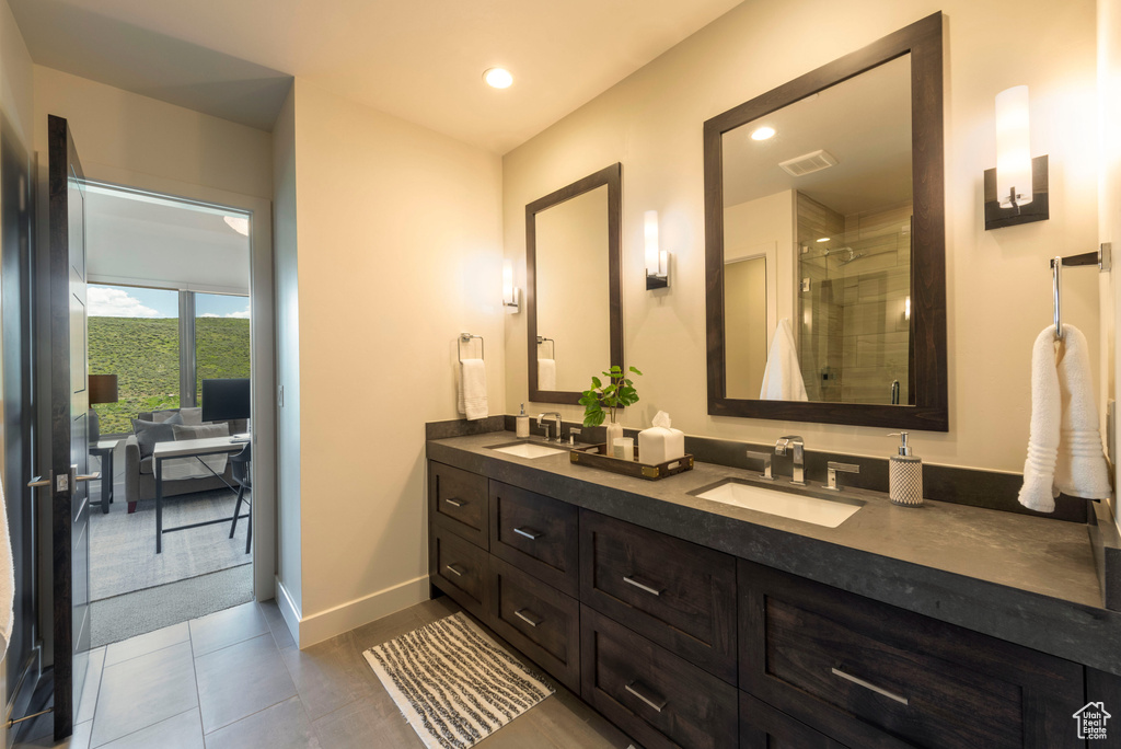 Full bathroom featuring double vanity, a stall shower, baseboards, recessed lighting, and tile patterned flooring