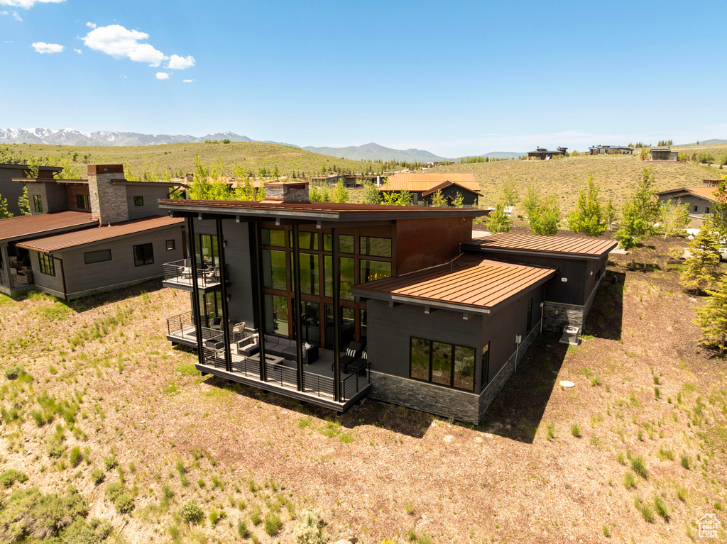 Rear view of house with a mountain view, stone siding, a chimney, a standing seam roof, and metal roof