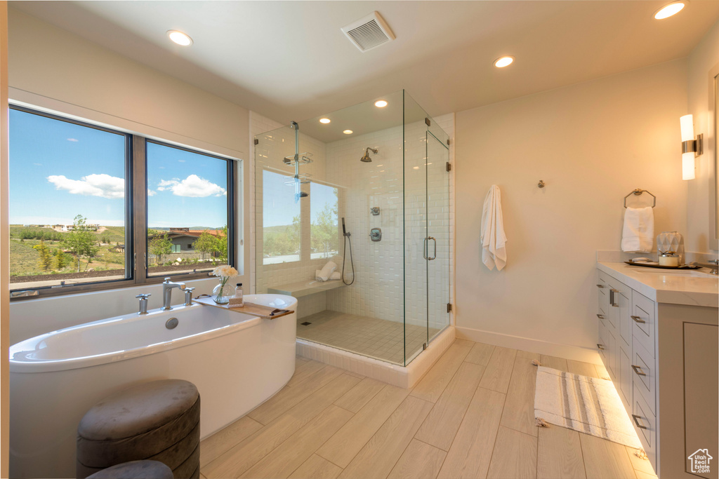 Full bath with a freestanding tub, a shower stall, vanity, wood finished floors, and recessed lighting