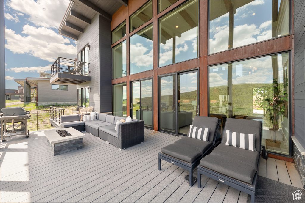 Wooden terrace with grilling area and an outdoor living space with a fire pit