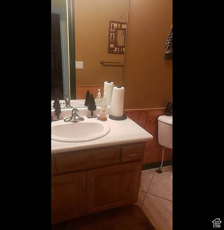 Half bathroom with vanity, toilet, and tile patterned flooring